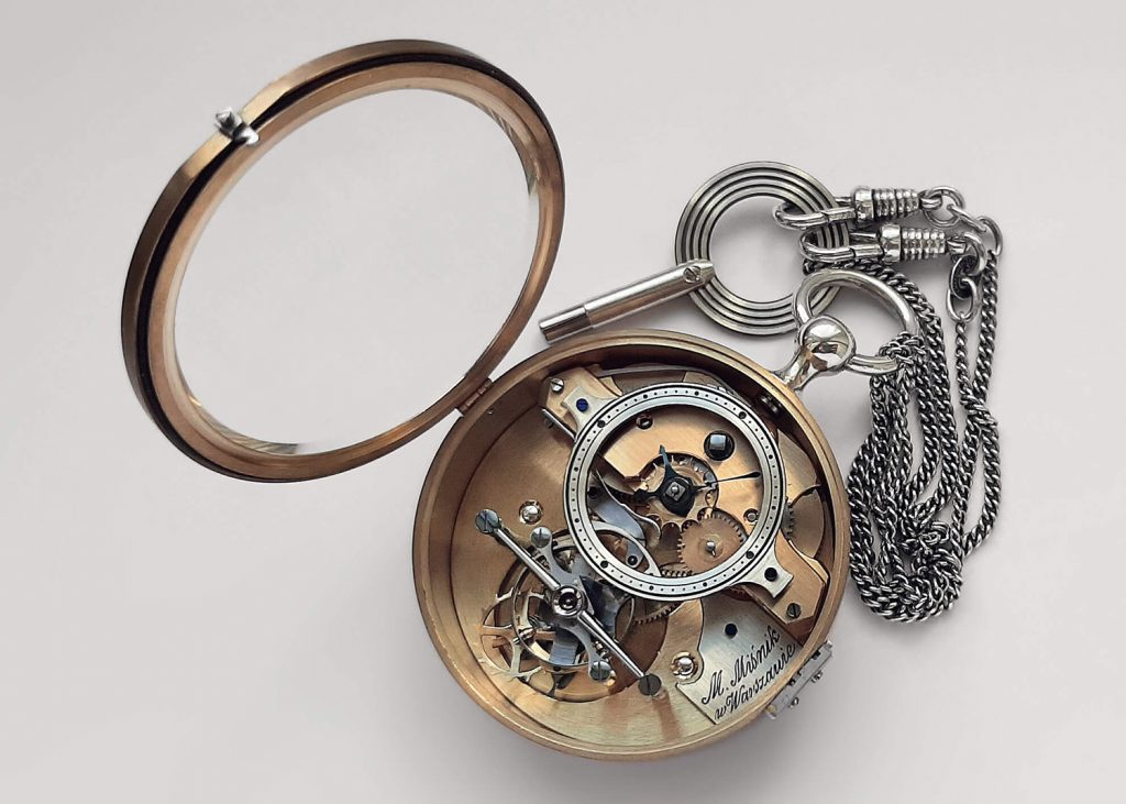 Brass pocket watch with silver pendant and key.