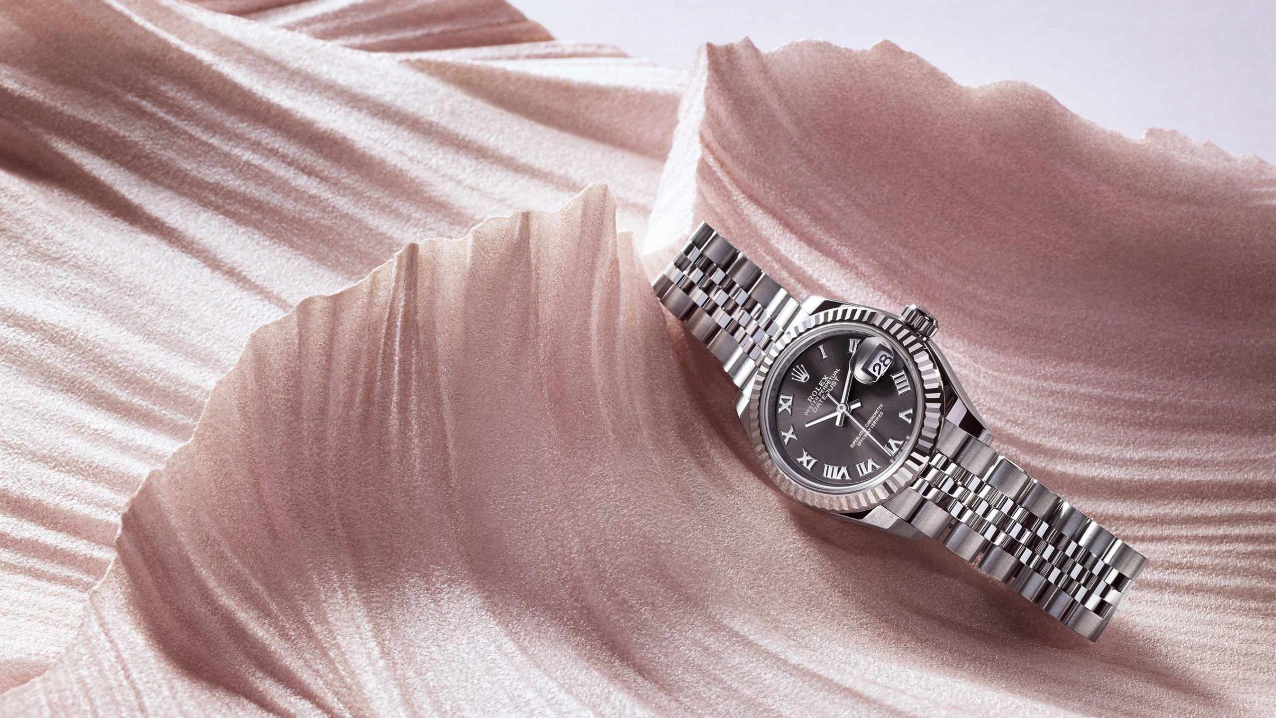 Rolex Lady Datejust in Rolesor steel against pink textured background